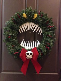 a wreath decorated with fake teeth and red bow hanging on the front door for halloween