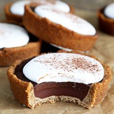 several desserts with white frosting on them sitting on top of a piece of parchment paper