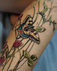 a close up of a butterfly on a flower with leaves and flowers around it's legs