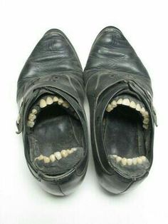 an open pair of black shoes with teeth on the bottom and inside, against a white background