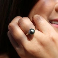 a close up of a person wearing a ring with a black pearl on it's middle finger