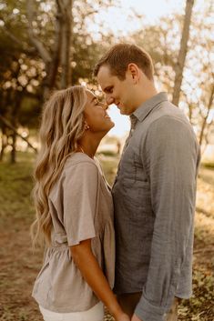 a man and woman standing next to each other in front of trees with the sun shining on them