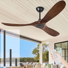 a person holding a remote control in front of a ceiling fan