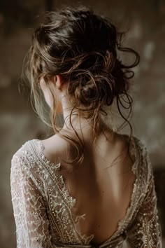 a woman with her hair in a low bun is wearing a white lace wedding dress