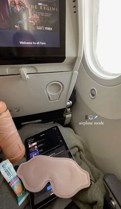 an airplane seat with various items on it and a flat screen tv in the back