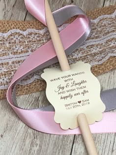 a pink and grey ribbon tied to a wooden stick with a wedding message on it