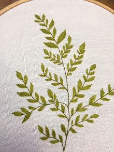 a close up of a embroidery on a piece of cloth with a plant in the middle