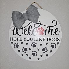 a welcome sign hanging on the wall with a dog's paw print and bow