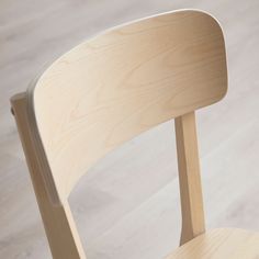 a wooden chair sitting on top of a hard wood flooring covered floor next to a white wall