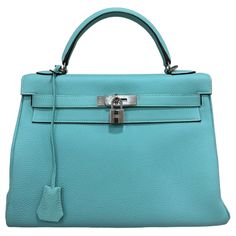 Borsa firmata Hermès, modello Kelly, misura 32, realizzata in pelle Clemence, morbida al tatto con grana grossa, nella colorazione Blue Atoll. Dotata di una patta con chiusura ad incastro con fascia orizzontale, lucchetto e clochette con chiavi. Munita di un manico centrale per portata a mano e di una tracolla rimovibile per indossare la borsa a spalla. Caratterizzata da hardware argento, internamente rivestita in pelle tono su tono, molto capiente con presenza di tasche con e senza zip. Anno di produzione 2014, si presenta in ottime condizioni. Hermès handbag, Kelly model, size 32, made of Clemence leather, soft to the touch with a coarse grain, in the Blue Atoll color. Equipped with a flap with interlocking closure with horizontal band, padlock and clochette with keys. Equipped with a ce Kelly 32, Clothing Ideas, Handle Bag, Bags Shoes, Fashion Handbags, Top Handle, Top Handle Bag, Chanel, Purses And Bags