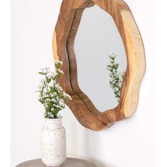 a wooden mirror sitting on top of a table next to a vase filled with flowers