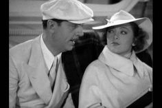 a man and woman sitting next to each other wearing hats on their heads while looking at each other