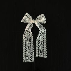 two white lace bows tied on top of each other in front of a black background