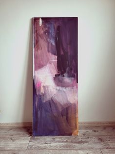 an abstract painting in purple and pink on a wall next to a potted plant