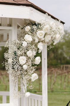 white roses and baby's breath hanging from a gazebo