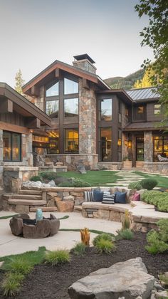 a large stone house with lots of windows and landscaping around the front yard, as well as an outdoor seating area