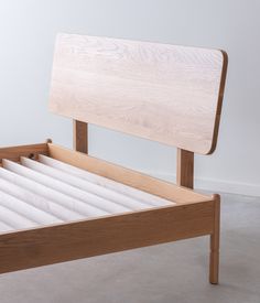 a wooden bed frame with white sheets on it