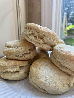 a stack of biscuits sitting on top of a white plate next to an open window