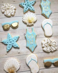 decorated cookies are laid out on a wooden table with sunglasses, starfish, and flip flops