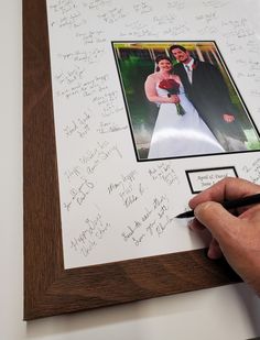 a hand holding a pen writing on a wedding photo