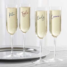 three champagne flutes with names on them sitting on a plate