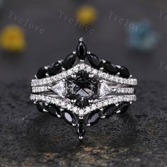 a black and white diamond ring set on top of a stone surface with yellow flowers in the background