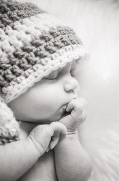 a black and white photo of a baby in a crocheted hat with the caption's name on it