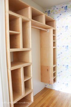 an empty closet with wooden shelves in the corner and wallpapered walls behind it