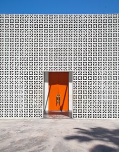 an orange door sits in front of a white wall with geometric designs on it's sides