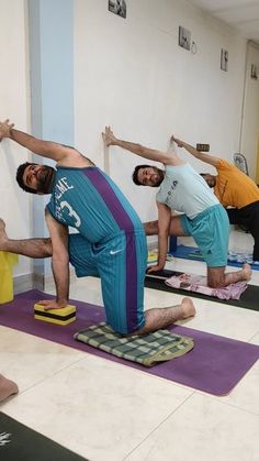 people doing yoga poses on mats in a room