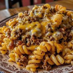 a plate full of pasta with ground beef and cheese on top, sitting on a table