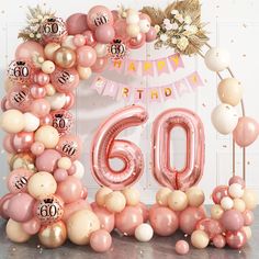 a pink and white balloon arch with the number sixty surrounded by balloons