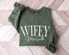 Personalized Wifey Sweatshirt, New Wife Sweatshirt, Mrs Shirt, Bride To Be Gift, Honeymoon Hoodie, Custom Mrs Sweatshirt,  Bridal Party Gift Hello Everyone! Welcome to NewTeeApparel. We are thrilled to have you here at our shop. At NewTeeApparel, you will find an extensive array of affordable, top-quality personalized designs and one-of-a-kind creations perfect for surprising your friends, family, coworkers, and loved ones. Our prints are meticulously crafted using the latest cutting-edge materials, ensuring exceptional quality and vibrant colors. Each order is prepared with the utmost care, employing top-quality inks during the production process. T-shirts hold a special place in our hearts as they allow us to convey significant moments, cherished memories, and sometimes express sentiment Wife Sweatshirt, Bride Hoodie, Bride Personalized, Name Sweatshirt, Wifey Sweatshirt, Mrs Sweatshirt, Bride Sweatshirt, Gifts For Fiance, Couples Sweatshirts