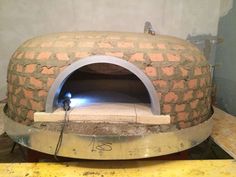 a brick oven sitting in the middle of a room next to a table with a light on it