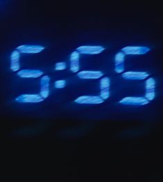 a digital clock with blue numbers displayed on it's display screen in the dark