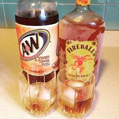 two glasses and a bottle of fireball on a counter top with ice cubes