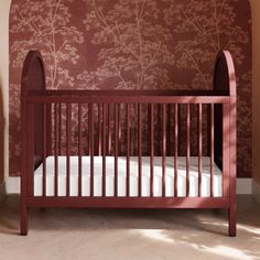 a baby crib in the corner of a room with a wallpapered background