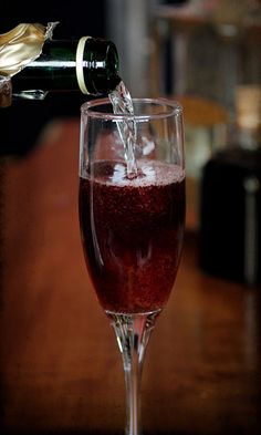 a wine glass filled with red liquid being poured into it