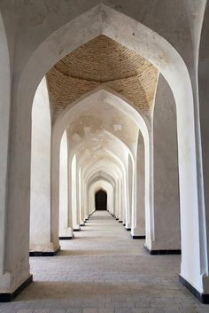 an arched hallway with white walls and tile flooring