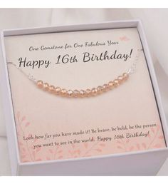 a birthday card in a box with a silver chain and gold beaded necklace on it