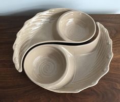 two white bowls sitting on top of a wooden table