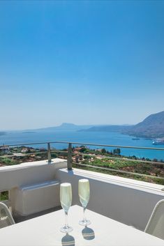 two glasses of wine sitting on top of a white table next to an ocean view