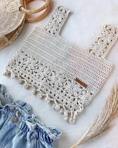 the crocheted purse is next to some straw hats and other items on a white surface