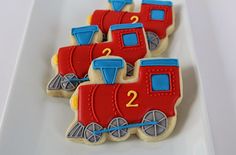 three decorated train cookies on a white plate