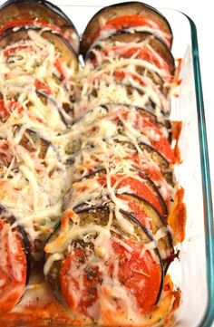 a casserole dish with tomatoes, cheese and sauce in it on a white surface