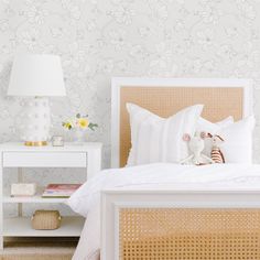 a white bed sitting next to a nightstand with a lamp on it's side