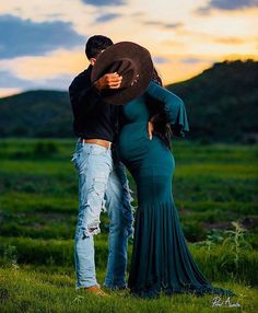 a man and woman are standing in the grass with their arms around each other as they hug