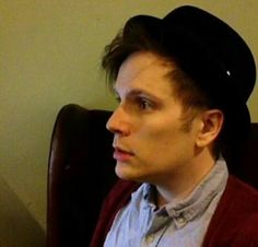 a young man wearing a black hat while sitting in a chair