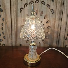 a glass lamp on a wooden table next to a wall