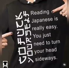 a person wearing a black t - shirt with japanese writing on it pointing at the screen